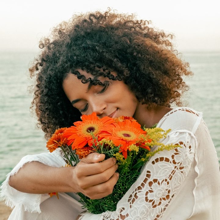 Lady breathing in a orange and yellow beautiful bouquet of flowers